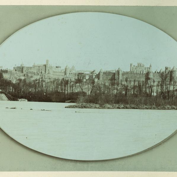 Carcassonne : La Cité. Photographies sépia. Le front nord-ouest, avec au premier plan la rivière d'Aude en crue lors des inondations de 1891. 13 cm x 18 cm. 1891.